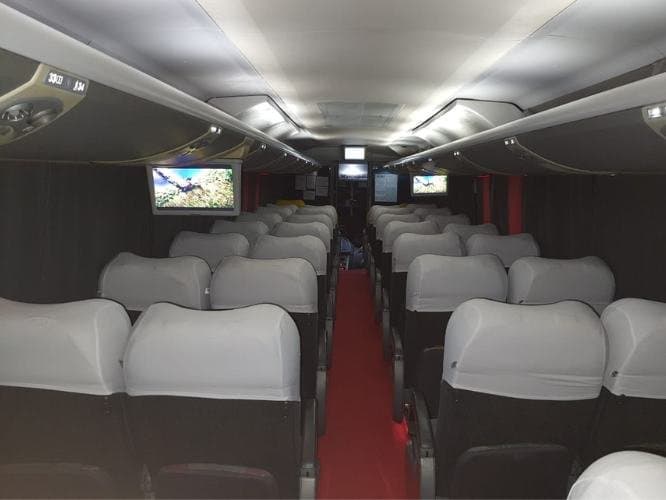 Interior de ônibus executivo com poltronas reclináveis e telas